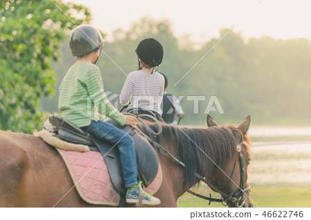 Kids learn to ride a horse near the river Kids learn to ride a horse near the river 46622746