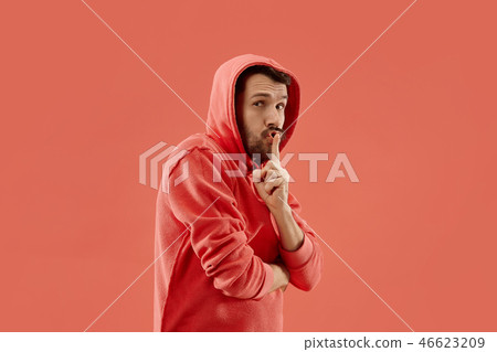 The young man whispering a secret behind her hand over coral background The young man whispering a secret behind her hand over coral background 46623209