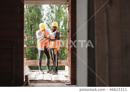 Happy Coworkers Laughing With Smartphone In Construction Site 46623311