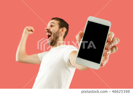 Young handsome man showing smartphone screen isolated on coral background in shock with a surprise 46625398