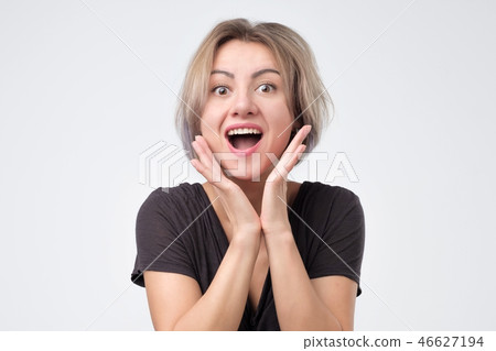 Young woman looking excited holding her mouth opened, hands on head. 46627194