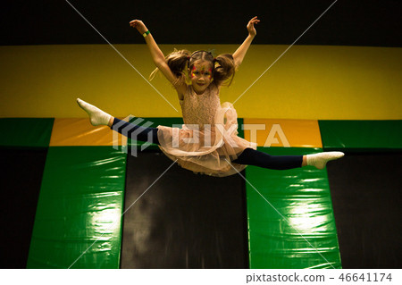 Little girl jumping on a trampoline and making twine split in play room for kids Little girl jumping on a trampoline and making twine split in play room for kids 46641174