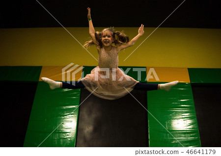 Little girl jumping on a trampoline and making twine split in play room for kids Little girl jumping on a trampoline and making twine split in play room for kids 46641179
