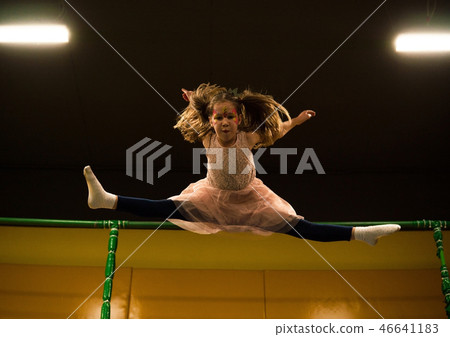 Little girl jumping on a trampoline and making twine split in play room for kids Little girl jumping on a trampoline and making twine split in play room for kids 46641183