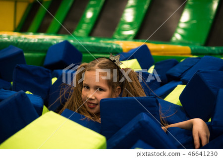 Little girl having fun in a dry pool with bright soft cubes to jump into. Kids playing room Little girl having fun in a dry pool with bright soft cubes to jump into. Kids playing room 46641230