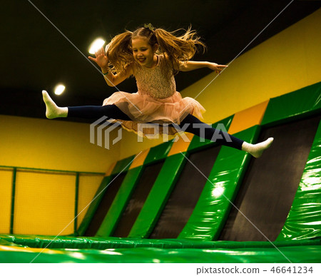 Little girl jumping on a trampoline and making twine split in play room for kids Little girl jumping on a trampoline and making twine split in play room for kids 46641234
