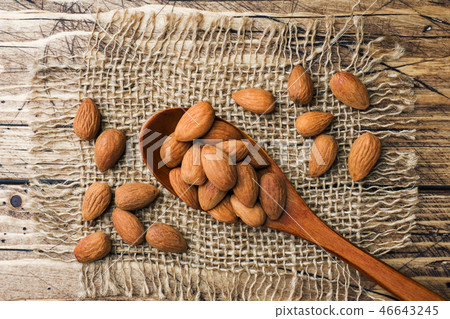 Almonds in wooden spoon on wooden background.  46643245