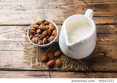 Almonds in a bowl and milk on the table.  46643255