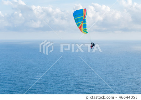 Flying a tandem paraglider over the sea with views of the horizon Flying a tandem paraglider over the sea with views of the horizon 46644053