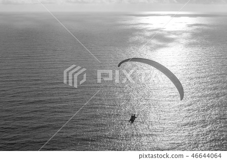 Silhouette flying tandem paragliders over the sea at sunset 46644064