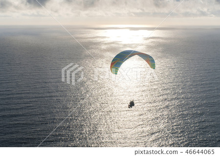 Silhouette flying tandem paragliders over the sea at sunset 46644065