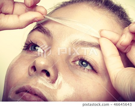 Woman removing facial peel off mask. 46645643