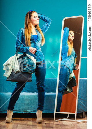 Fashion woman wearing blue denim in front of mirror Fashion woman wearing blue denim in front of mirror 46646389