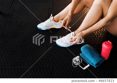 woman tying shoelaces of sneakers in the gym woman tying shoelaces of sneakers in the gym 46657813