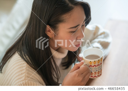 Young Japanese Woman Drinking Hot Drink In Room 46658435