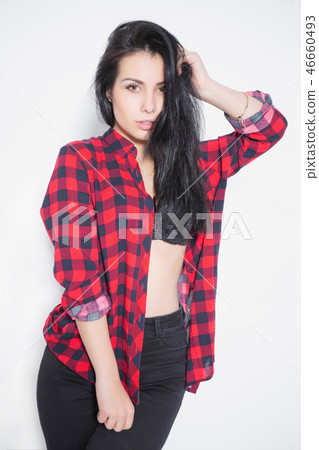 Pensive young brunette posing in a plaid shirt. Pensive young brunette posing in a plaid shirt. 46660493