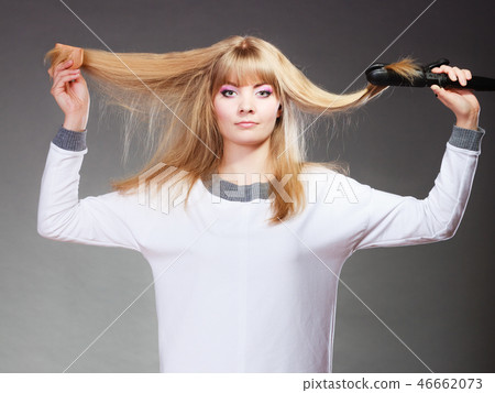 woman making hairstyle with hair iron 46662073