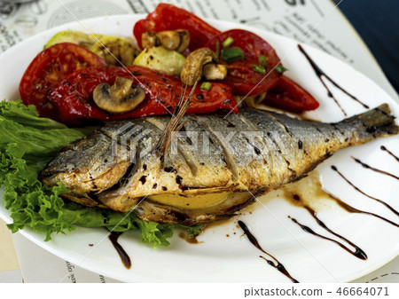 Fried fish with grilled tomatoes and lemon. Small depth of field 46664071