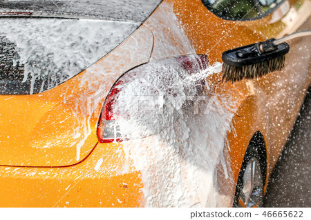 Yellow car washed in carwash, soap & foam spraying 46665622