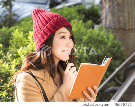 Thinking woman holding an orange notebook 46666735