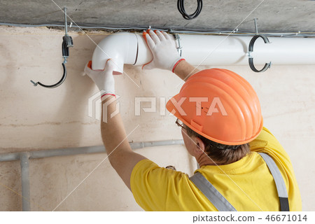 The worker is installing a ventilation system. The worker is installing a ventilation system. 46671014
