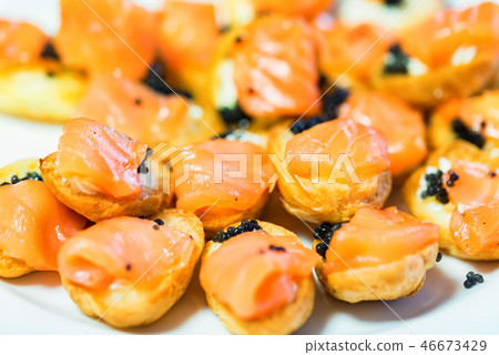 Delicious profiteroles with black caviar and salmon on a plate close-up Delicious profiteroles with black caviar and salmon on a plate close-up 46673429