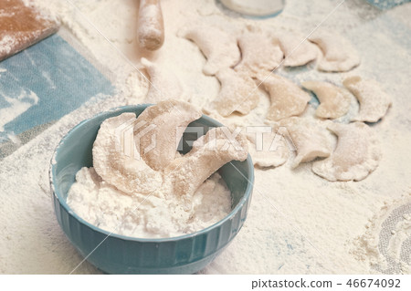 Ravioli on table sprinkled with flour and blue bowl with cottage cheese Ravioli on table sprinkled with flour and blue bowl with cottage cheese 46674092