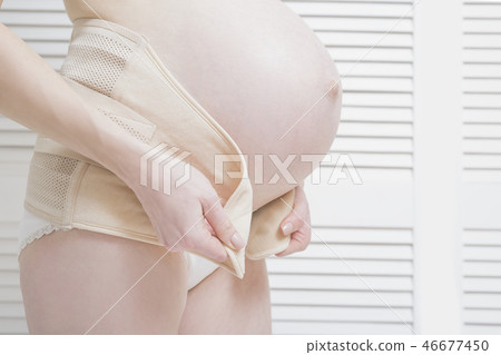 Woman puts on a bandage for pregnant women Woman puts on a bandage for pregnant women 46677450