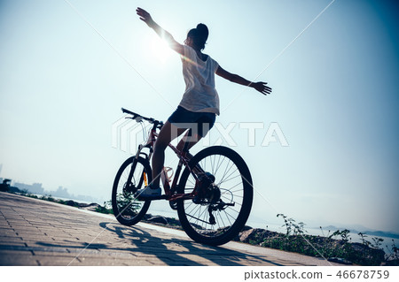 Hands free cycling woman riding bike on seaside 46678759