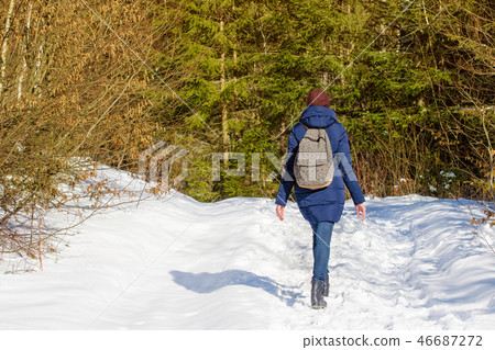 Girl with backpack walking in a snowy forest 46687272