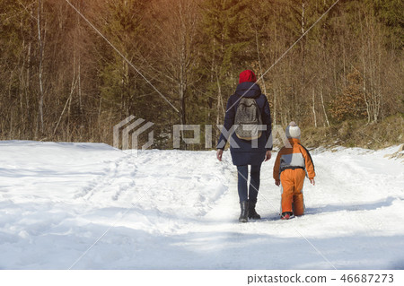 Mother withlittle son walking along snow-covered 46687273