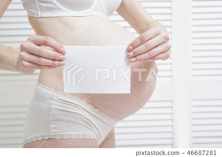 Pregnant woman is holding a white blank sheet Pregnant woman is holding a white blank sheet 46687281