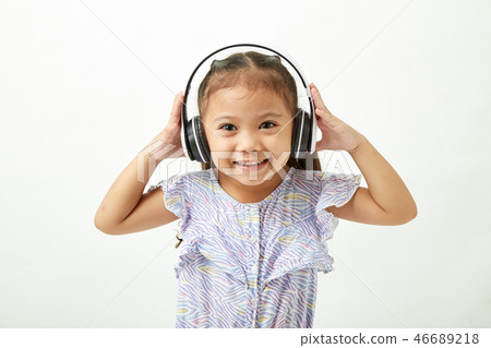 little girl listening to music on headphones 46689218