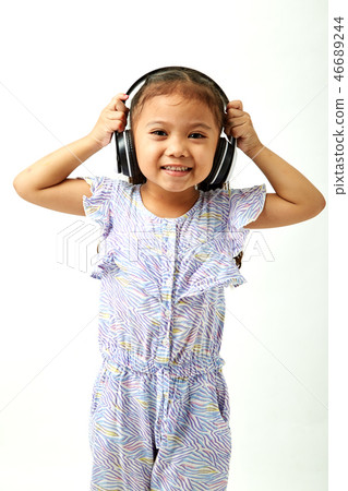little girl listening to music on headphones 46689244