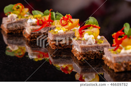 A canape from black bread with fillet from a guine A canape from black bread with fillet from a guine 46689782