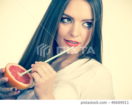 Woman holds grapefruit drinking juice from fruit Woman holds grapefruit drinking juice from fruit 46689911