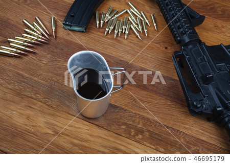 rifle and cup of coffee on wooden table 46695179