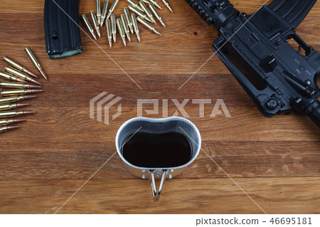 rifle and cup of coffee on wooden table 46695181
