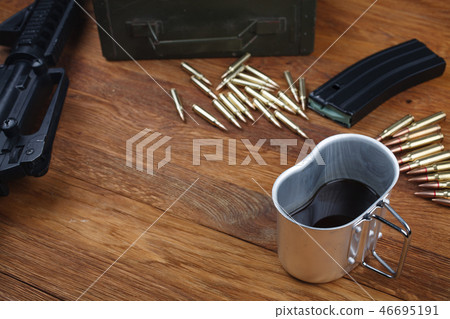 rifle and cup of coffee on wooden table 46695191