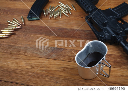assault rifle and cup of coffee on wooden table assault rifle and cup of coffee on wooden table 46696190