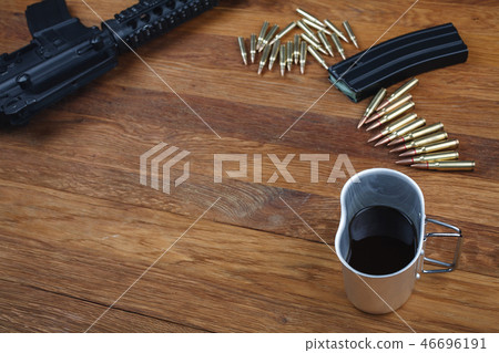 assault rifle and cup of coffee on wooden table 46696191
