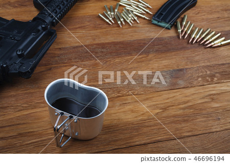 assault rifle and cup of coffee on wooden table 46696194