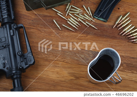 assault rifle and cup of coffee on wooden table assault rifle and cup of coffee on wooden table 46696202