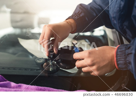 Close-up of a professional windshield repairman working with hydraulic polymer crack filler Close-up of a professional windshield repairman working with hydraulic polymer crack filler 46696830