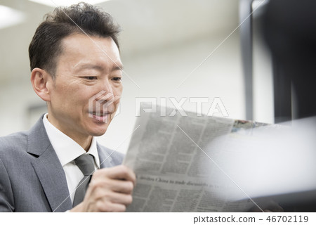 Businessman reading an English newspaper 46702119