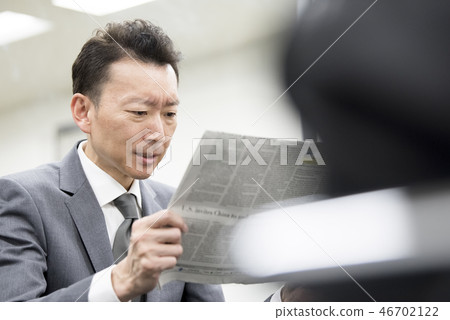 Businessman reading an English newspaper Businessman reading an English newspaper 46702122
