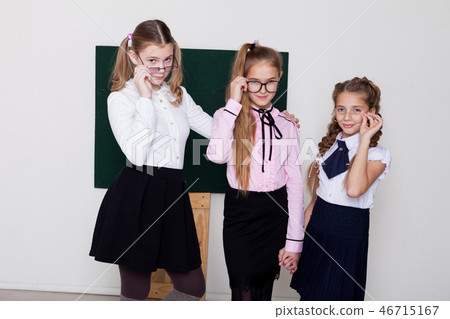 three girls schoolgirl is standing at the Blackboard with lesson 46715167