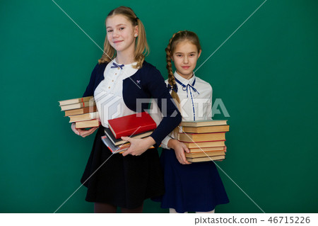 two girls schoolgirl is standing at the Blackboard with lesson books 46715226