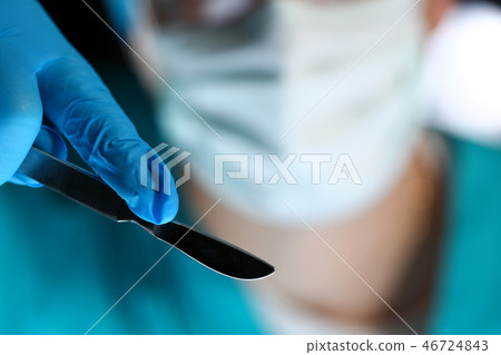 Surgeon arms in sterile uniform holding sharp knife Surgeon arms in sterile uniform holding sharp knife 46724843