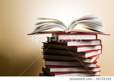 An open book on a stack of red books in the form of a spiral. 46726169